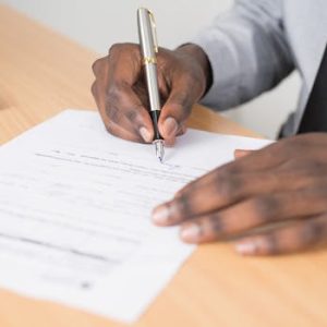 Close-up of a businessman signing a contract at an office desk.